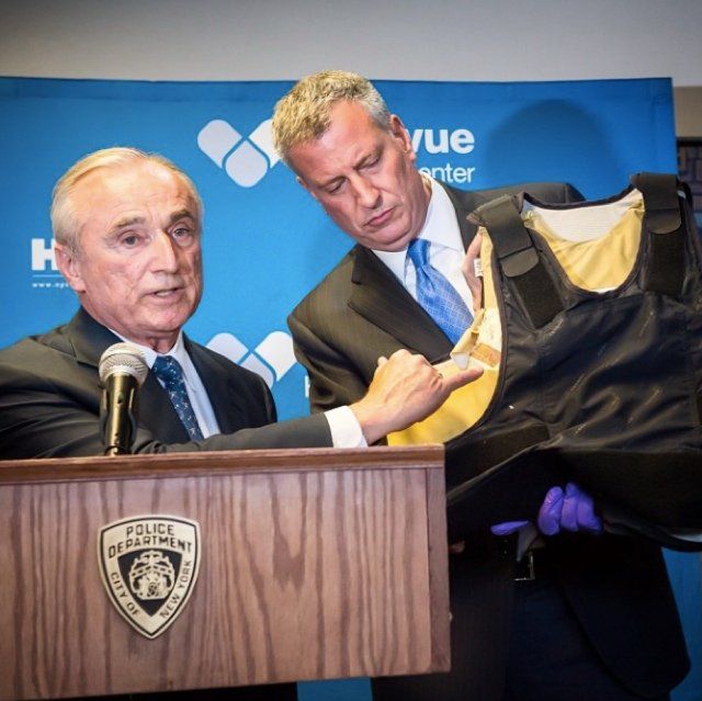 Bratton and Mayor de Blasio show the bulletproof vest the detective was wearing when he got shot (NYC Mayor's Office)